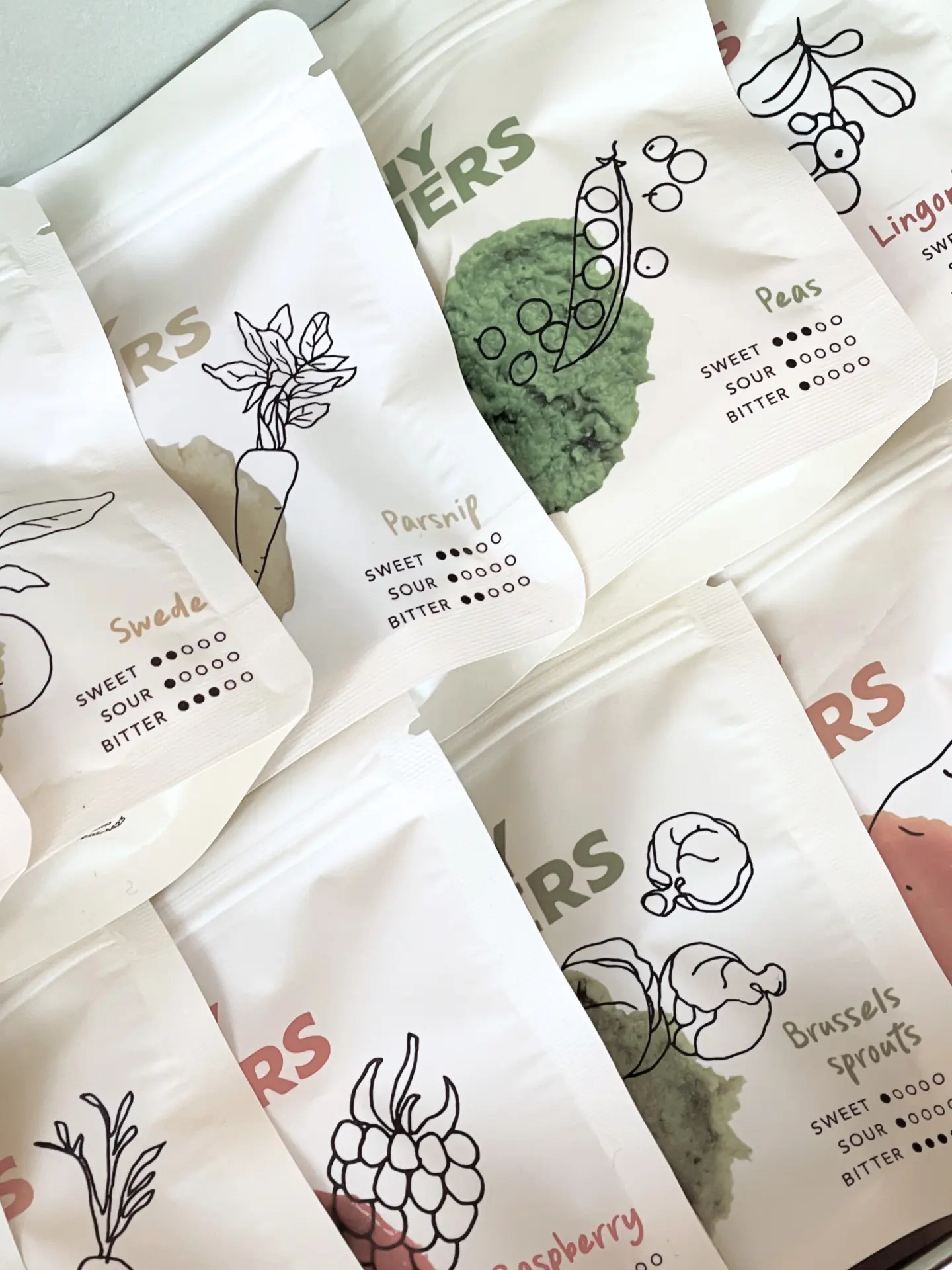 Close-up of Tiny Fingers flavour pouches: parsnip, peas, swede, raspberry and Brussels sprouts